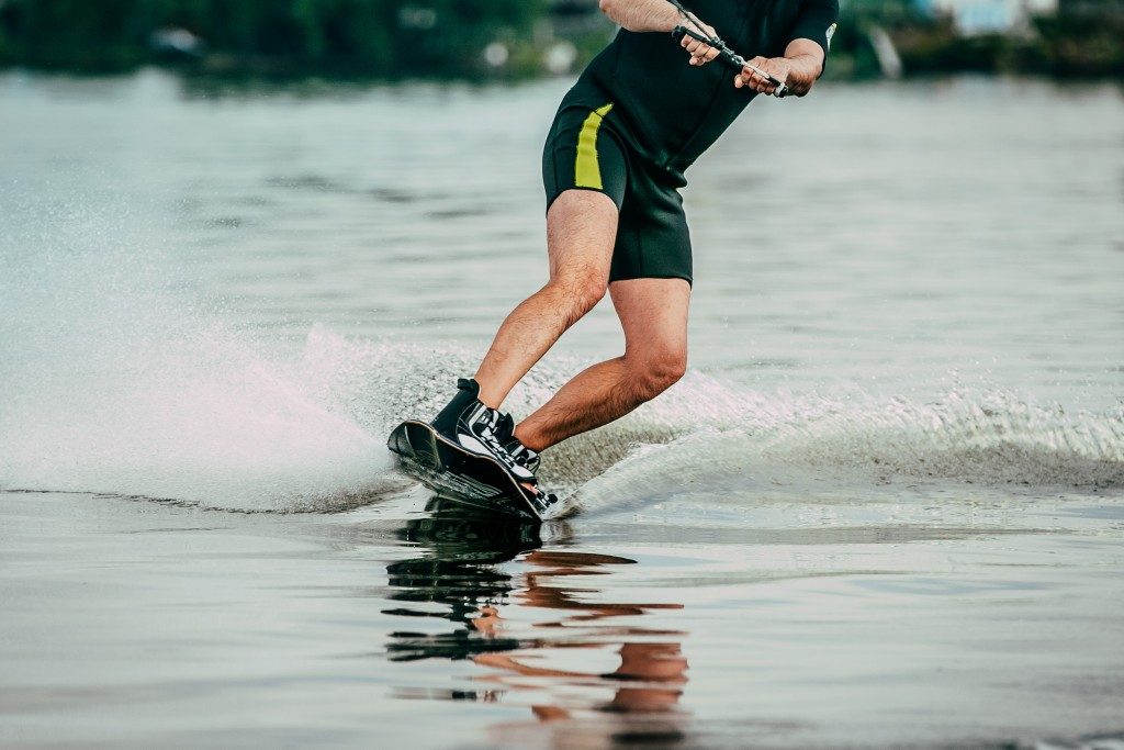 male athlete rides on a wakeboard on lake in summer