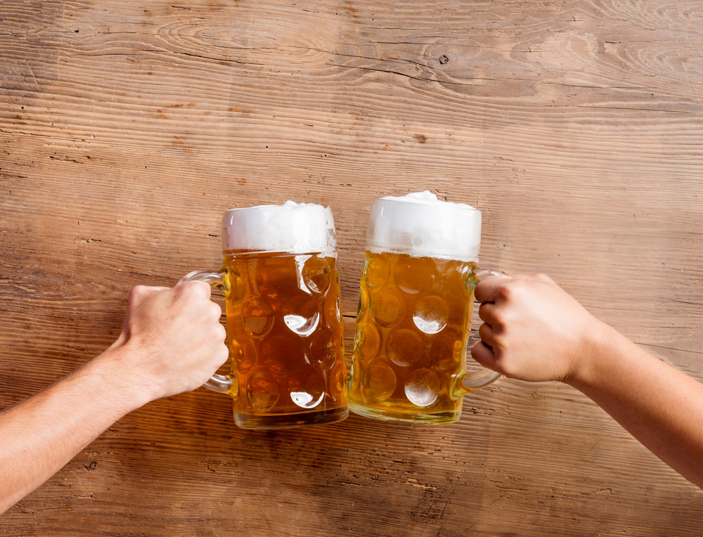 Two unrecognizable men clinking with beer mugs, studio shot